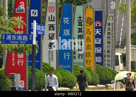 ---- Fußgänger vorbei an Schildern von chinesischen und ausländischen Unternehmen in der Lujiazui Finanzviertel in Pudong, Shanghai, China, 12. Stockfoto