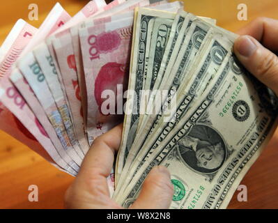 ---- Eine chinesische Bewohner zählt seine RMB (Renminbi) Yuan und US Dollar Banknoten in Qionghai City, South China Hainan Provinz, 15. März 2014. Chi Stockfoto