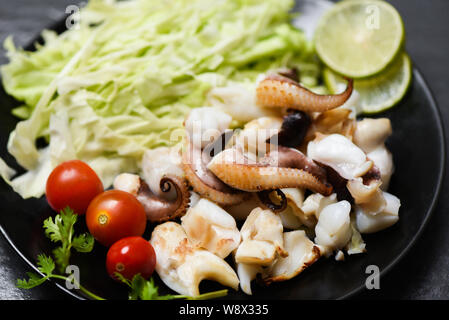 Tintenfisch Salat mit Zitrone Kräuter und Gewürze auf Esstisch/Tentakeln Krake warme Vorspeise essen heiß und würzig Meeresfrüchte zubereitet auf dem Teller im serviert. Stockfoto