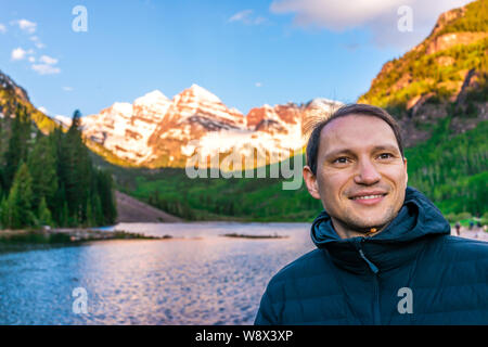 Maroon Bells See bei Sonnenaufgang mit glücklichen Mann in Aspen, Colorado während der Blauen Stunde der Dämmerung mit Rocky Mountain Peak und Schnee Stockfoto