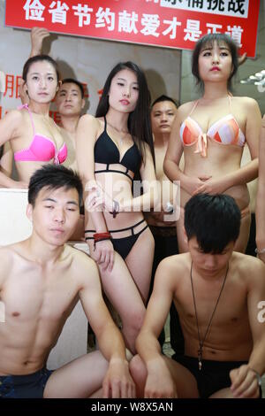 Chinesische Mitarbeiter gekleidet in Bikinis und Badehosen den Eimer für das Eis Herausforderung Boykott in ihrem Büro in Shenzhen City, South China Guan Stockfoto