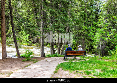 Vail, USA - 29. Juni 2019: Resort Stadt in Colorado mit Senior Paar sitzt auf der Bank von Gore Creek River und Pinien Stockfoto