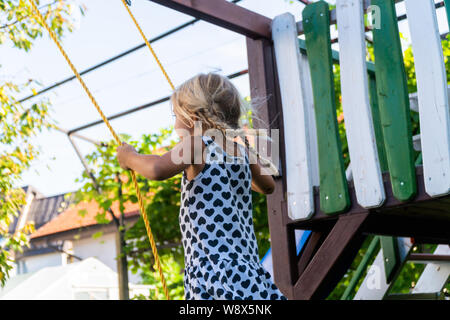 3-5 jährige blonde Mädchen Spaß haben auf einer Schaukel im Freien. Sommer Spielplatz. Mädchen Schwingen hoch. Junge Kind auf der Schaukel im Garten Stockfoto