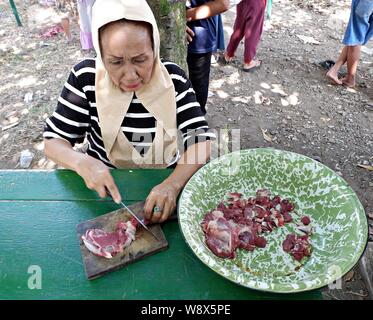 Eine muslimische Frau zerlegtes Fleisch auf einem Schneidebrett. Stockfoto