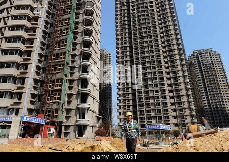 ---- Ein chinesischer Wanderarbeiter Spaziergänge Vergangenheit high-rise apartment Gebäude auf der Baustelle ein Wohnprojekt in Qingdao Stadt, Osten Kinn Stockfoto