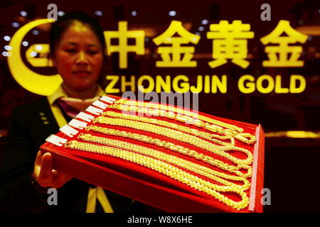 ---- Eine chinesische Angestellte zeigt Gold Halsketten in einem Geschäft von Zhongjin Gold in Qingdao Stadt, East China Provinz Shandong, 16. Dezember 2013. China's l Stockfoto