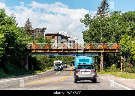 Aspen, USA - Juni 27, 2019: Snowmass Village Stadt in Colorado mit Schnee Berge und Autos im Verkehr Straße Straße auf Sommer sonnigen Tag Stockfoto