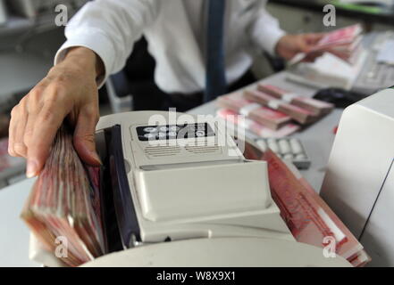 ---- Eine chinesische Angestellte verwendet eine Cash - Zählmaschine RMB (Renminbi) Yuan Banknoten bei einer Filiale der Landwirtschaftlichen Bank von China (ABC) Qiongha zu zählen Stockfoto
