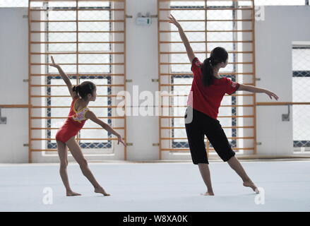 Ein Trainer, rechts, leitet ein junges Mädchen während einer Ausbildung an der gymnstics Fuyang Sport Schule in Fuyang Stadt zu üben, der ostchinesischen Provinz Anhui, Stockfoto