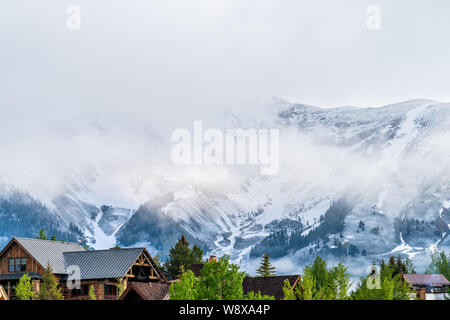 Mount Crested Butte, USA Colorado Dorf im Sommer mit Wolken und Nebel Nebel Sonnenaufgang morgen und Häuser auf Hügeln mit grünen Bäumen, Stockfoto