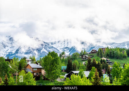 Mt Crested Butte, USA Colorado Dorf im Sommer mit Wolken und Nebel Nebel Sonnenaufgang morgen und Häuser auf Hügeln mit grünen Bäumen, Stockfoto