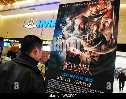 ---- Eine Chinesische filmgoer betrachtet ein Plakat des Films, The Hobbit: The Desolation von Smaug, in einem Kino in Kunshan City, Central China Hubei prov Stockfoto