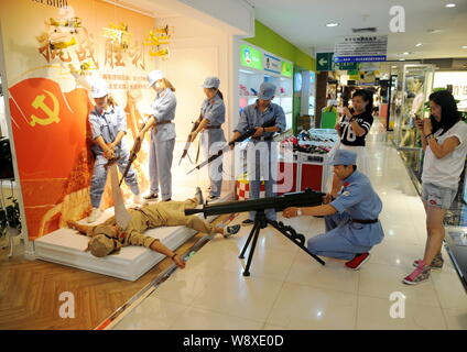 Chinesische Beamte in blauen Uniformen des 8. Route Armee verwenden Spielzeugpistolen gekleidet an einen Mitarbeiter in einer Uniform der japanischen Armee während t gekleidet zu Ziel Stockfoto