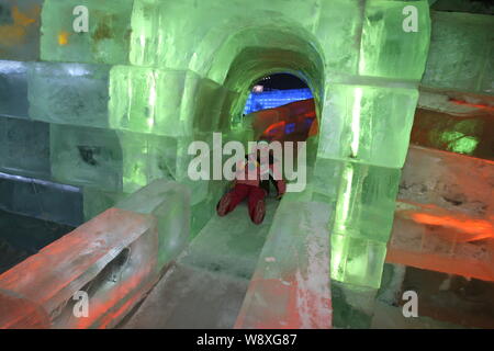 Ein Besucher rutscht eine eisskulptur am 30. Harbin International Eis und Schnee Festival in der Stadt Harbin, Provinz Heilongjiang, China Stockfoto