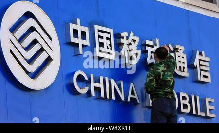 ---- Ein chinesischer Arbeiter reinigt eine Tafel von China Mobile in Zhoukou City, Central China Provinz Henan, 22. März 2014. Chinas größter Telecom o Stockfoto