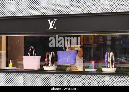 ---- Eine chinesische Reinigung Arbeitnehmer Stäube aus einem Zähler zur Schau stellen Handtaschen und andere Zubehörteile können Sie bei einem Fashion Store von Louis Vuitton (LV) in Fuzhou cit Stockfoto