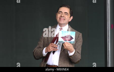 Englisch Schauspieler Rowan Atkinson zeigt ein Foto von China Pavillon, als er Mr. Bean während der Dreharbeiten für einen Werbespot im Mercedes-Benz Ar spielt Stockfoto