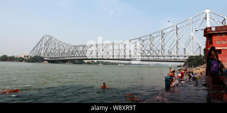 Menschen, die an einem Ghat, Baden, Howrah Bridge, Hooghly River, Kolkata, Westbengalen, Indien Stockfoto