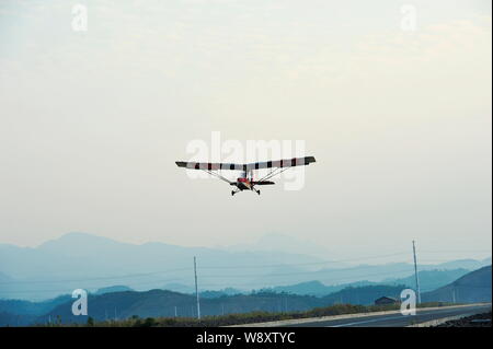 Pensionierte chinesischen Arzt Jin Shaozhi fliegt seine chinesischen Honigbiene-3C super leichtes Flugzeug über einem Highway in Jinyun County, Lishui City, East China Zhe Stockfoto