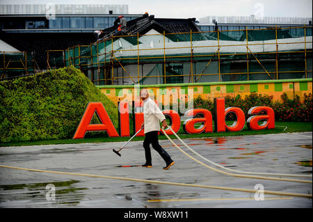 --FILE - eine Reinigung Arbeitnehmer Spaziergänge vorbei an einer Tafel von Alibaba am Sitz der Chinesischen e-commerce Riese Alibaba Group in Hangzhou, China Stockfoto