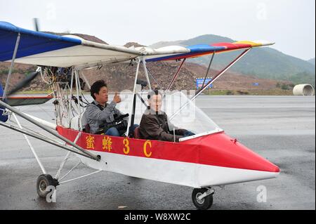 Pensionierte chinesischen Arzt Jin Shaozhi, rechts, beginnt seine chinesischen Honigbiene-3C super leichtes Flugzeug ein Videofilmer auf einem Highway unter constructi durchführen Stockfoto