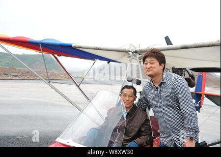 Pensionierte chinesischen Arzt Jin Shaozhi, Links, saß in seinem chinesischen Honigbiene-3C super leichtes Flugzeug wirft mit ein Videofilmer auf einem Highway unter const Stockfoto