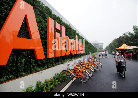 Ein deliveryman Fahrten hinter einer Tafel von Alibaba Group in Hangzhou City, East China Zhejiang provinz, 26. Juni 2014. Der New York Stock Exchange Stockfoto