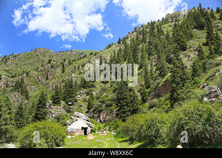 Die Jurte ist die traditionelle Behausung der Nomaden in den malerischen Bergen, an einem sonnigen Sommertag. Stockfoto