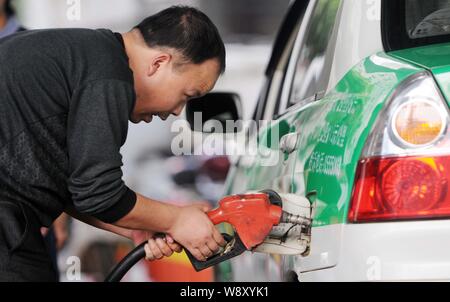 ------ Fahrer tankt sein Auto an einer Tankstelle in Conghua City, East China Provinz Jiangxi, 26. März 2014. China wird die USA überholen wie die Stockfoto