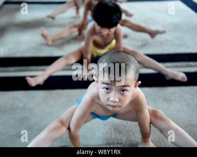 Junge chinesische Jungs verbiegen ihre Körper mit ihren Händen auf dem Boden zu halten Gymnastik an einer Gymnastik Training Center in Bozhou ci zu üben Stockfoto