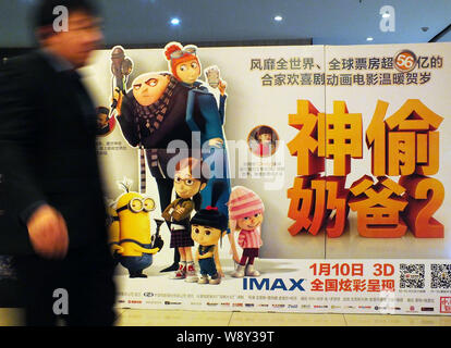 ---- Ein kinogänger Spaziergänge hinter einem Plakat des Films, Despicable Me2, in einem Kino in Kunshan City, Central China Provinz Hubei, 8. Januar 2014. C Stockfoto