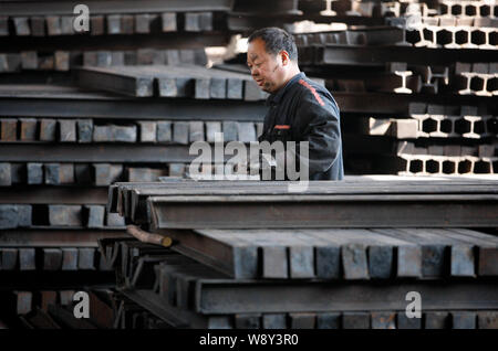 ---- Ein chinesischer Arbeiter untersucht einen Stapel von Stahlerzeugnissen in einem Verarbeitungsbetrieb in Stadt Huaibei, East China Provinz Anhui, 4. April 2014. Ich Stockfoto