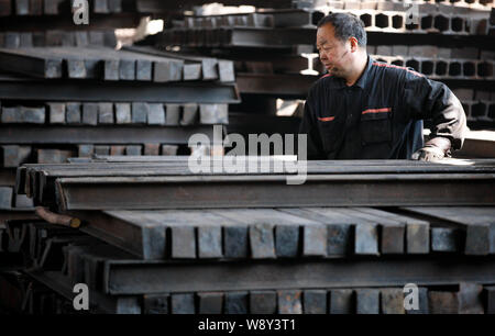 ---- Ein chinesischer Arbeiter untersucht einen Stapel von Stahlerzeugnissen in einem Verarbeitungsbetrieb in Stadt Huaibei, East China Provinz Anhui, 4. April 2014. Stockfoto