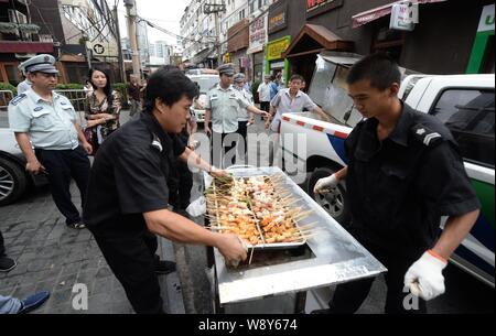 ------ Chinesische Offiziere von der Beijing Municipal Bureau von Stadtverwaltung und Polizei beschlagnahmt ein Grill und Nahrung an einem strassenrand barbec Stockfoto