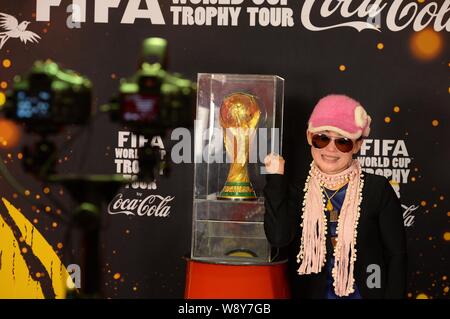 Ein chinesischer Besucher stellt mit einer Nachbildung der FIFA WM-Pokal während der FIFA World Cup Trophy Tour in Shanghai, China, 9. April 2014. Stockfoto