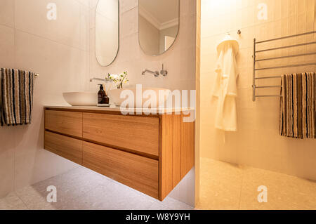 Luxus inländischen Badezimmer Dusche und Waschtisch mit Eiche Kommode Schubladen, zwei Waschbecken, weißen Farbschema und heller Beleuchtung bei Nacht Stockfoto