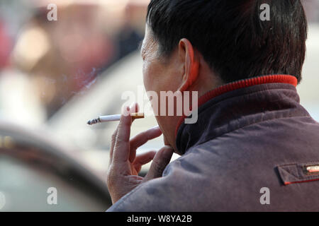 --FILE - Ein chinesischer Mann raucht eine Zigarette an einem öffentlichen Ort in Nantong, der ostchinesischen Provinz Jiangsu, 30. November 2013. China erwägt Raisin Stockfoto