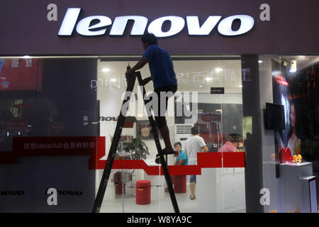 ---- Ein chinesischer Arbeiter reinigt das Namensschild an einem Speicher von Lenovo in Peking, China, 11. August 2013. Lenovo Group Ltd., der Weltgrößte Hersteller Stockfoto