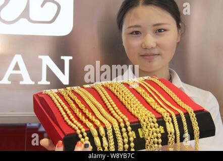 ---- Eine chinesische Angestellte zeigt Gold Halsketten an einem Juwelier in Lanzhou City, East China Jiangsu Provinz, den 3. August 2014. Global gold Nachfrage Stockfoto