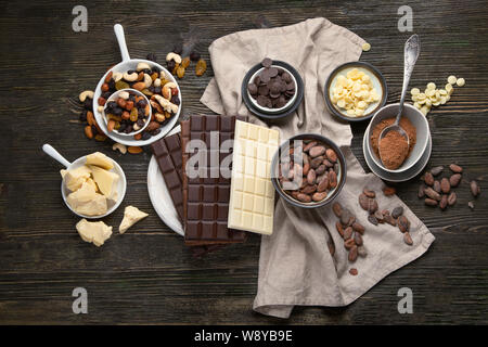 Dunkle bitter, Milch und weiße Schokolade, Kakao Butter, Kakao Pulver und Bohnen auf Holztisch. Ansicht von oben Stockfoto