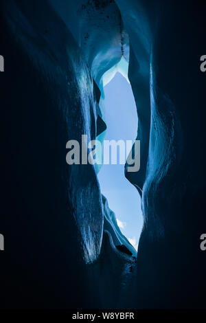 Blick von der dunklen in einer Eishöhle in Alaska. Gletschergrotte auf der Matanuska Gletscher. Geschwungene Wände und eisigen Detail dark blue Ice. Stockfoto