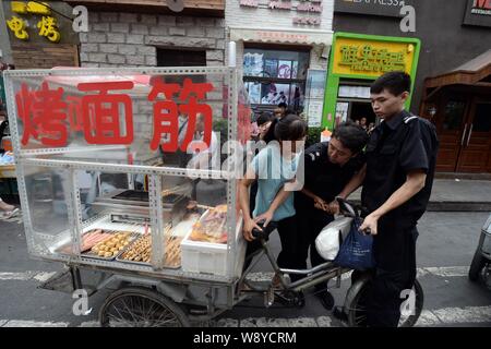 ------ Chinesische Offiziere von der Beijing Municipal Bureau von Stadtverwaltung und Polizei beschlagnahmt ein Dreirad einen Grill Anbieter Abschaltdruck Stockfoto