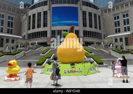 Leute schauen auf die riesigen Birne, verziert mit mehr als 15.000 Gummienten vor dem Grand Gateway Plaza in Shanghai, China, 30. Mai 2014. Ein 6-me Stockfoto