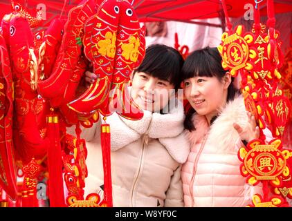 Kunden kaufen rot Dekorationen für die bevorstehende chinesische Mondjahr oder Spring Festival auf einem Markt in Stadt Bozhou, East China Provinz Anhui, 29 Ja