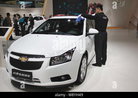 ---- Ein chinesischer Arbeiter Stäube aus einem Chevrolet Cruze Hatchback von Shanghai GM, ein Joint Venture zwischen der SAIC Motor und General Motors, auf Anzeige durin Stockfoto