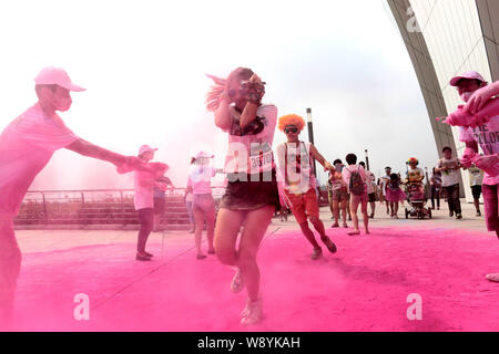 Die Teilnehmer werden durch Mitarbeiter mit farbigem Pulver gesprüht, wie Sie durch eine Farbe Station während der fünf Kilometer langen Colour run Ereignis in Shangha ausführen Stockfoto