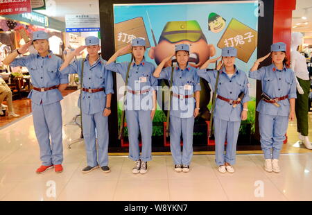 Chinesische Beamte in blauen Uniformen des 8. Route Armee salute während einer Werbekampagne in einer Shopping Mall in Changchun Stadt gekleidet, North China Stockfoto