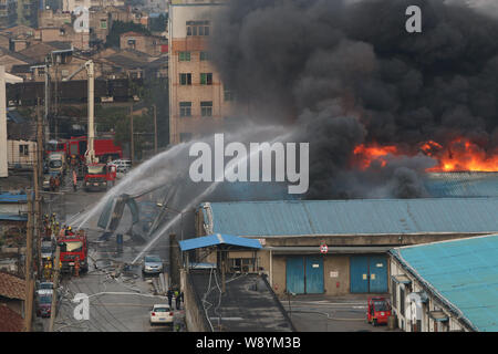 Chinesische Feuerwehrmänner Schlauch Wasser das Feuer durch Explosionen in der chemischen Warehouses verursacht zu löschen, verletzt drei Menschen, an der Wenzhou chemischen Markt Stockfoto