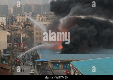 Chinesische Feuerwehrmänner Schlauch Wasser das Feuer durch Explosionen in der chemischen Warehouses verursacht zu löschen, verletzt drei Menschen, an der Wenzhou chemischen Markt Stockfoto