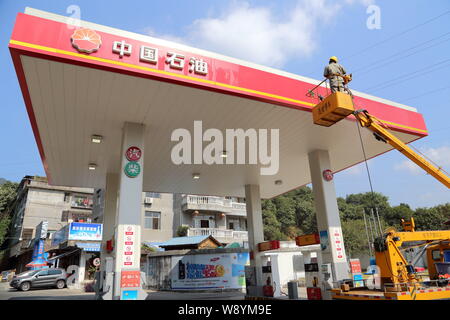 ---- Ein chinesischer Arbeiter reinigt die Tafel an einer Tankstelle von PetroChina, eine Tochtergesellschaft der CNPC (China National Petroleum Corporation), in Fuzhou c Stockfoto